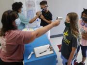 FILE - In this Tuesday, July 14, 2020 file photo, Amid concerns of the spread of COVID-19, teachers check students before a summer STEM camp at Wylie High School in Wylie, Texas. Not knowing if children are infected makes it difficult for schools to reopen safely, many experts say. Scarce data on whether infected children -- including those without symptoms -- easily spread the disease to others complicates the issue, said Jeffrey Shaman, a Columbia University infectious disease specialist.