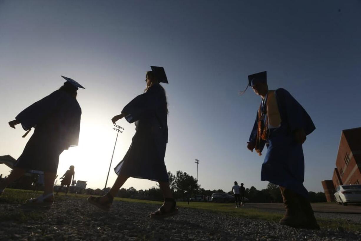 ADVANCE FOR PUBLICATION ON MONDAY, JULY 6, AND THEREAFTER - FILE - In this June 27, 2020, file photo, Saltillo High School seniors make their way to the football field as the sun begins to set for their graduation ceremony in Saltillo, Miss. The number of high school seniors applying for U.S. federal college aid plunged in the weeks following the sudden closure of school buildings this spring &#039;Ai a time when students were cut off from school counselors, and families hit with financial setbacks were reconsidering plans for higher education.