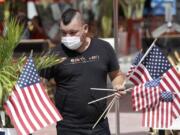 Marvin Turcios puts out American flags at Ocean&#039;s 10 restaurant on Miami Beach, Florida&#039;s famed Ocean Drive on South Beach, July 4, 2020. The Fourth of July holiday weekend began Saturday with some sobering numbers in the Sunshine State: Florida logged a record number of people testing positive for the coronavirus.