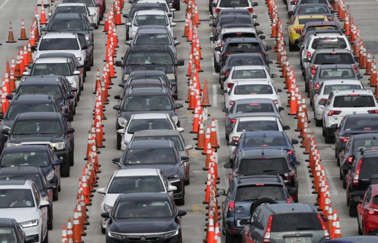 Lines of cars wait at a drive-through coronavirus testing site, Sunday, July 5, 2020, outside Hard Rock Stadium in Miami Gardens, Fla. Florida health officials say the state has reached a grim milestone: more than 200,000 people have tested positive for the novel coronavirus since the start of the outbreak.