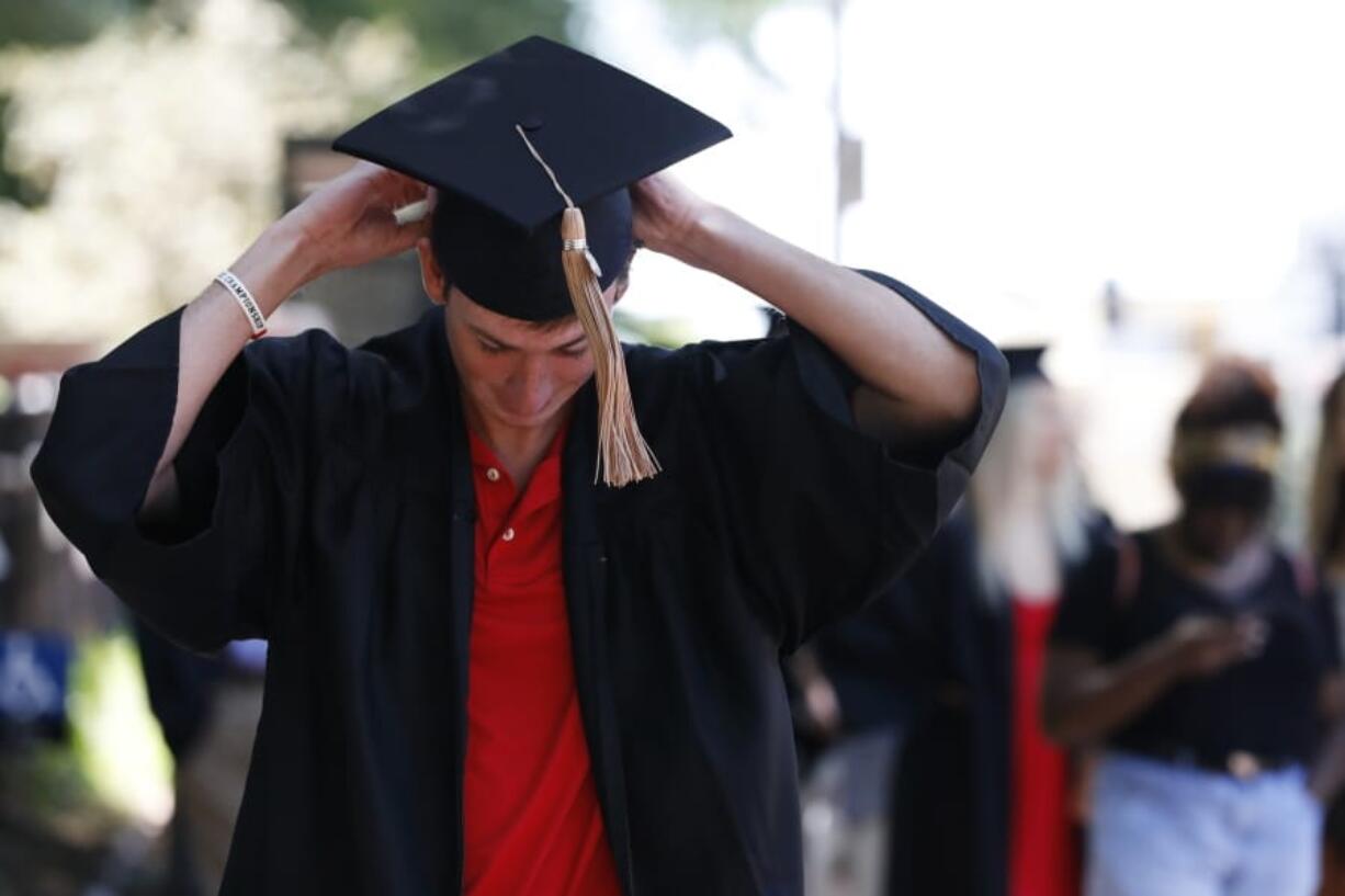 In this Thursday, May 7, 2020 photo, University of Georgia graduates line up to take photos at the University of Georgia arch  in Athens, Ga. The spring commencement, which would have been held on Friday, was moved to the fall due to the COVID-19 pandemic. (Joshua L.