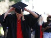 In this Thursday, May 7, 2020 photo, University of Georgia graduates line up to take photos at the University of Georgia arch  in Athens, Ga. The spring commencement, which would have been held on Friday, was moved to the fall due to the COVID-19 pandemic. (Joshua L.