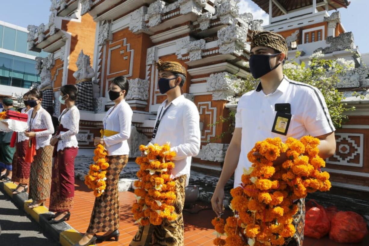 Airport officers wearing face masks line up as they hold flowers to welcome passengers at Bali airport, Indonesia on Friday, July 31, 2020. Indonesia&#039;s resort island of Bali reopened for domestic tourists after months of lockdown due to a new coronavirus.