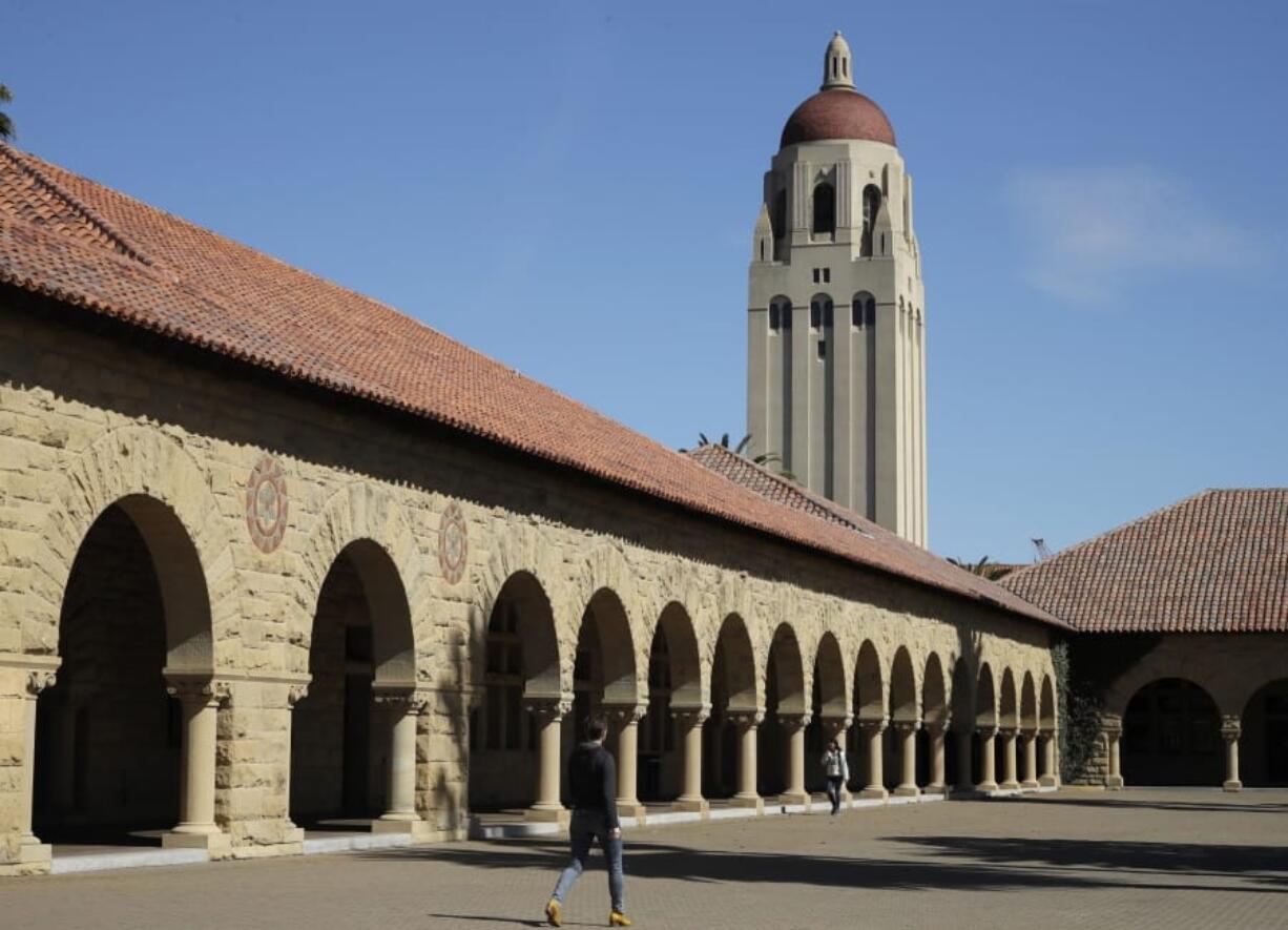 FILE- In this March 14, 2019, file photo, people walk on the Stanford University campus beneath Hoover Tower in Stanford, Calif. A week after revoking sweeping new restrictions on international students, federal immigration officials on Friday, July 24, 2020, announced that new foreign students will be barred from entering the United States if they plan to take their classes entirely online this fall.