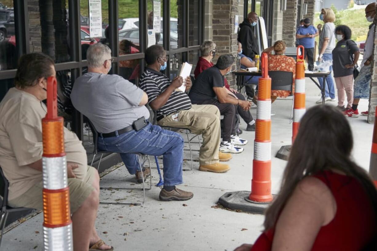 Job seekers exercise social distancing as they wait to be called into the Heartland Workforce Solutions office in Omaha, Neb., Wednesday, July 15, 2020. Nebraska reinstated job search requirements this week for most people claiming jobless benefits. Those unemployment insurance requirements were suspended in mid-March to help employees who had lost their jobs due to the coronavirus.