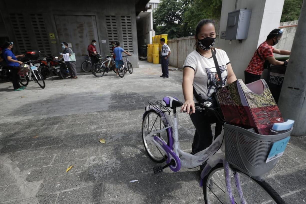 A recipient of a bicycle from the Benjamin Canlas Courage to be Kind Foundation pushes her bicycle outside a building at the financial district of Manila, Philippines, Saturday, July 11, 2020. Restricted public transportation during the lockdown left many Filipinos walking for hours just to reach their jobs. The foundation saw the need and gave away mountain bikes to nominated individuals who are struggling to hold on to their jobs in a country hard hit by the coronavirus.