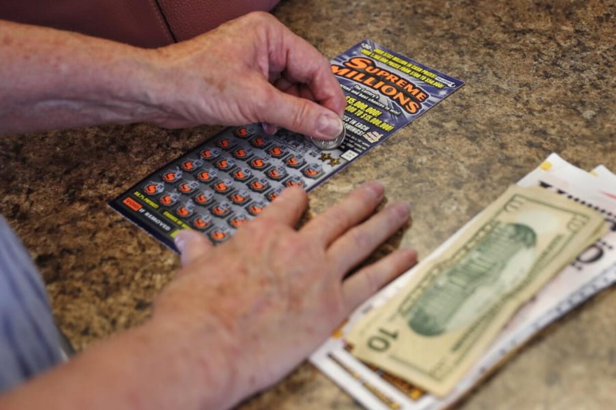 A woman scratches a $30 instant ticket while playing the lottery at Ted&#039;s Stateline Mobil on Wednesday, June 24, 2020 in Methuen, Mass. The coronavirus pandemic has been a rollercoaster for state lotteries across the country, with some getting a boost from the economic downturn and others scrambling to make up for revenue shortfalls.