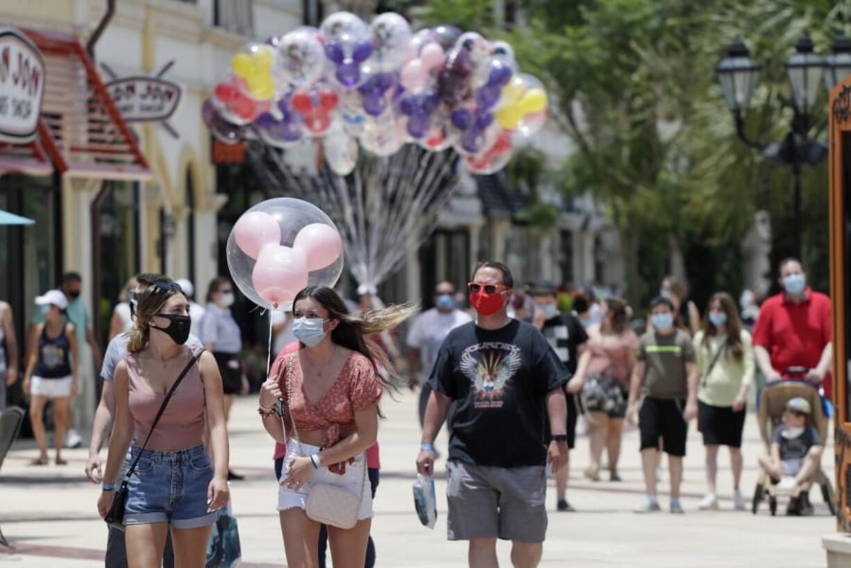 FILE - In this June 16, 2020, file photo, guests required to wear masks because of the coronavirus stroll through the Disney Springs shopping, dining and entertainment complex in Lake Buena Vista, Fla. Magic Kingdom and Animal Kingdom will reopen on July 11. In May, the company opened Disney Springs.