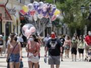 FILE - In this June 16, 2020, file photo, guests required to wear masks because of the coronavirus stroll through the Disney Springs shopping, dining and entertainment complex in Lake Buena Vista, Fla. Magic Kingdom and Animal Kingdom will reopen on July 11. In May, the company opened Disney Springs.