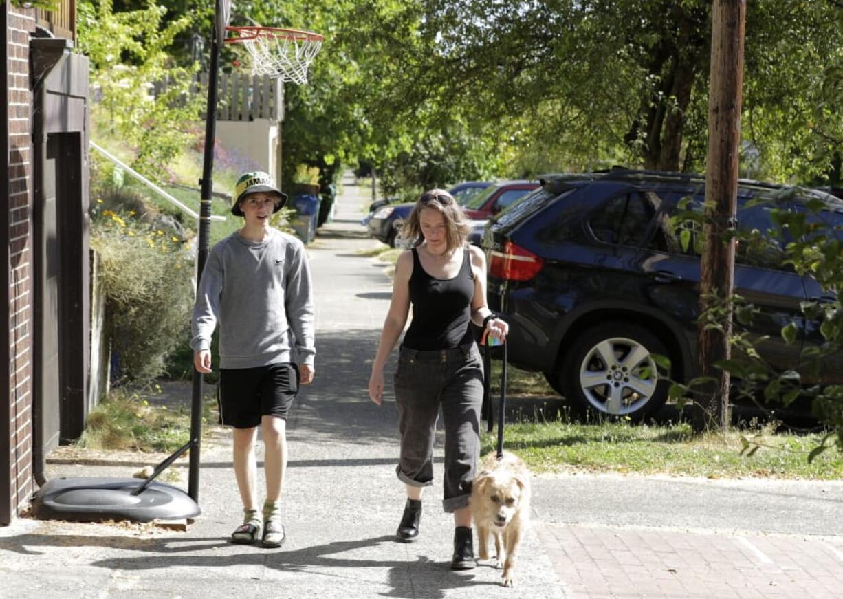 Jennifer Haller, right, the first person to receive a trial dose of a COVID-19 vaccine, walks with her son Hayden, 16, and their dog Meg, Sunday, July 19, 2020, in Seattle. As the world&#039;s biggest COVID-19 vaccine study gets underway more than four months after Haller and 44 others became the first participants in a phase-one coronavirus vaccine study that has produced encouraging results, Haller is encouraging other people to sign up for future trials. (AP Photo/Ted S.