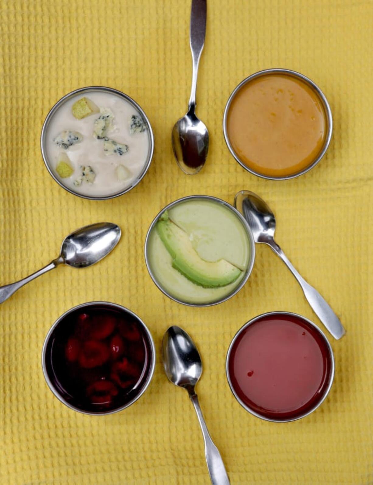 Summer soups, clockwise from top left: Chilled Stilton and Pear Soup, Cold Carrot-Coconut Soup, Lightly Spiced Tomato Soup, Cherry Soup, and center, Curried Avocado Soup. (Hillary Levin/St.