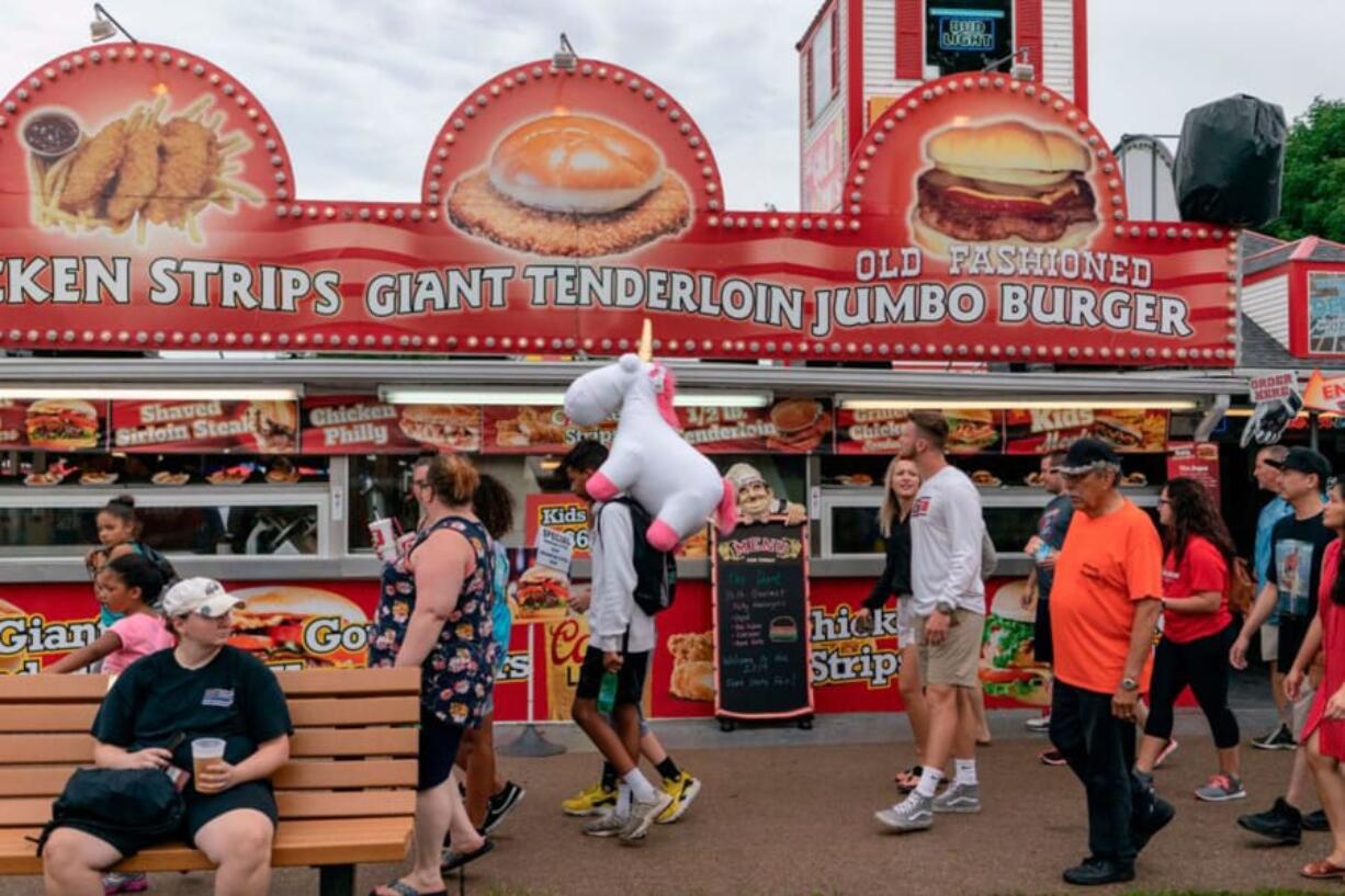 People walk past a food stand at the Iowa State Fair on August 11, 2019 in Des Moines, Iowa.