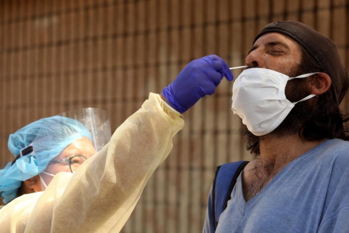 Nurse Richelle Legaspi, a member of the outreach team with The Center, gives Gonzalo Cresci, who is homeless, a test for COVID-19 in East Hollywood, California on August 18, 2020.