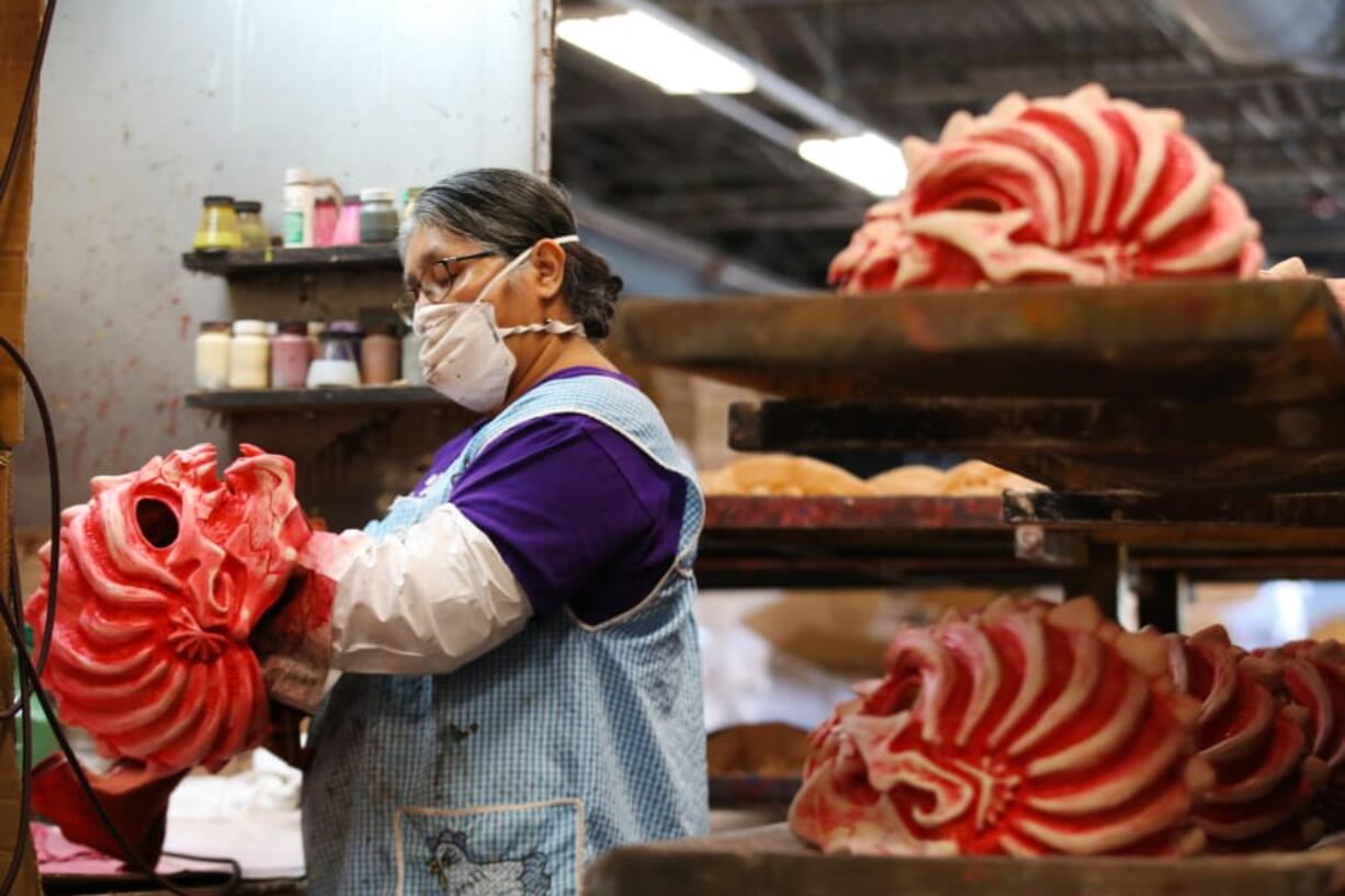 Rosa Romero dabs paint off of a Down to Earth mask at Zagone Studios on Thurs., Aug. 20, 2020 in Melrose Park. During a typical year they would produce 125,000 masks but not so this year because of coronavirus.  They have been making masks for 40 years.