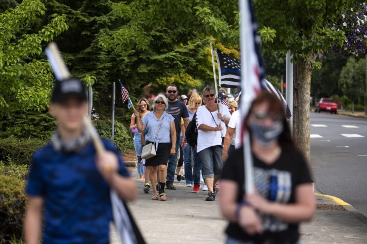 Community members march through downtown Ridgefield during a rally in support of local law enforcement Saturday. About 100 people attended the rally, which was organized by Derek Sommers of Ridgefield.