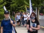 Community members march through downtown Ridgefield during a rally in support of local law enforcement Saturday. About 100 people attended the rally, which was organized by Derek Sommers of Ridgefield.