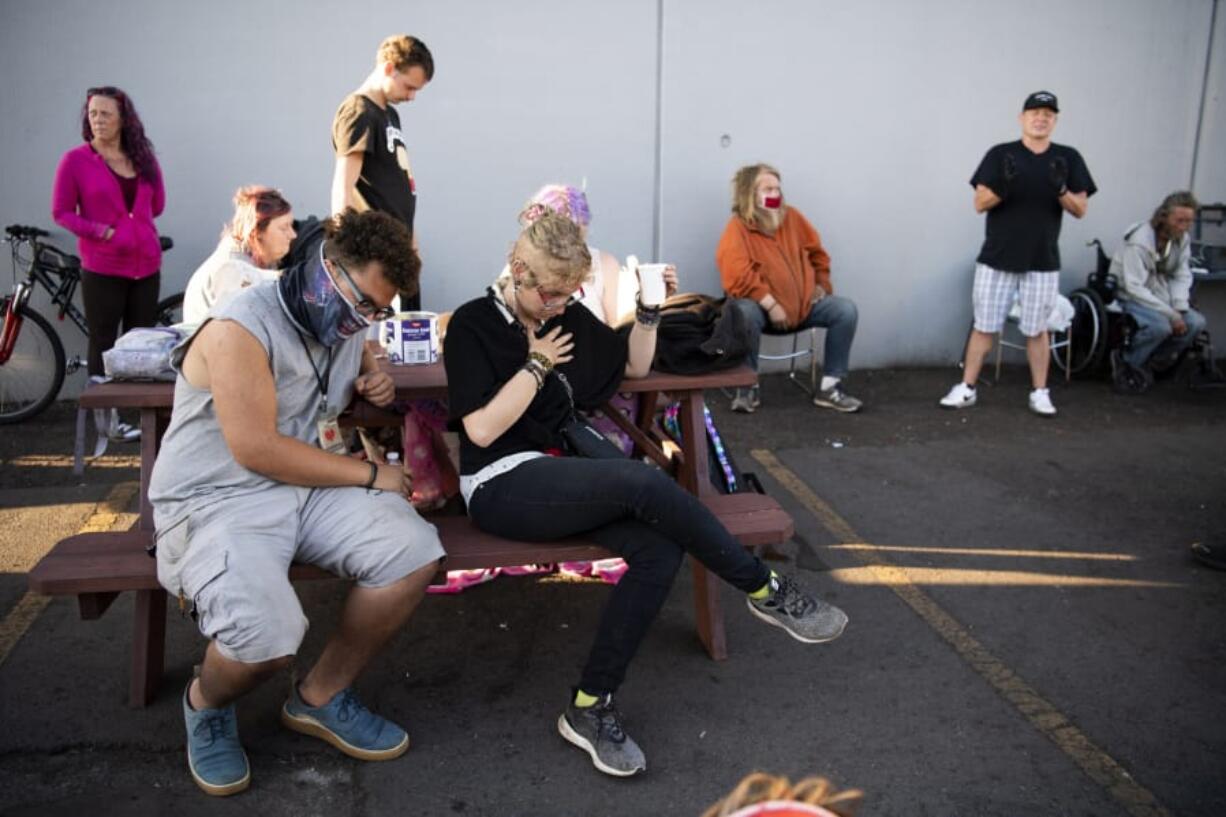 Pastor Brian Norris, in black shirt and cap, leads a prayer before serving a meal at Living Hope Church, where a temporary homeless encampment was set up in early May. It provides shelter, showers, snacks and restrooms to people without homes during the pandemic.