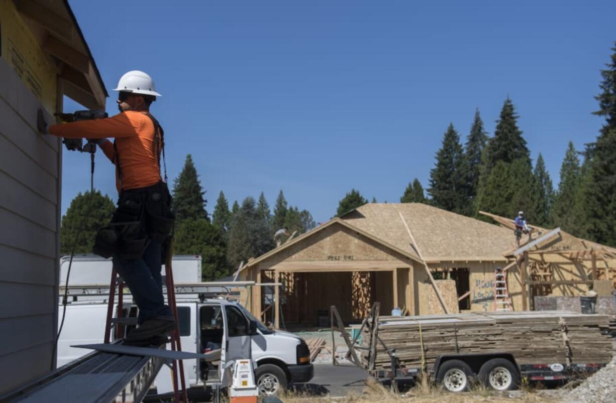 Construction worker Oscar Patino, left, works on the siding of a new home while lending a hand to the construction project at the Cedars community in Brush Prairie on Thursday morning. Clark County homebuilders say they&#039;re encountering shortages of critical materials such as lumber and appliances.