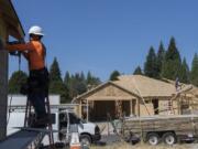 Construction worker Oscar Patino, left, works on the siding of a new home while lending a hand to the construction project at the Cedars community in Brush Prairie on Thursday morning. Clark County homebuilders say they&#039;re encountering shortages of critical materials such as lumber and appliances.