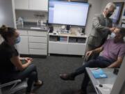 Elizabeth Miller, from left, current owner of Hearing by Design, looks on as consultant Rick Giles works with Don Stose, Mayor of Ridgefield, as he programs Stose&#039;s hearing aid response during an appointment.