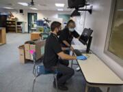 Vadim Zalyashko, left, and Jasmine John, who both work in technology services for Battle Ground Public Schools, set up a new computer to be used by a Battle Ground High School teacher remotely in the fall Tuesday morning. Clark County school districts are eligible for more than $13 million in federal coronavirus relief funds.