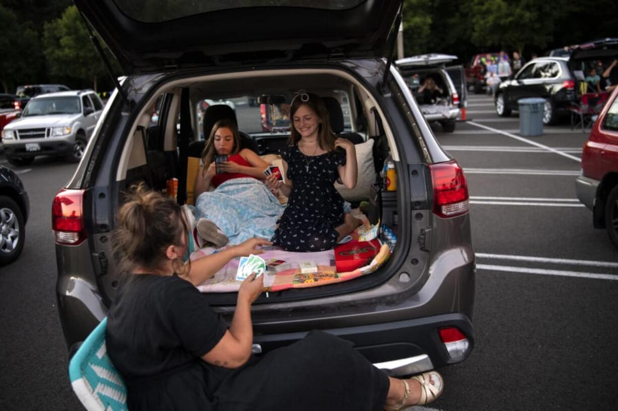 Chelsea Owen, from left, and her daughters Lou Asbury, 14, and Nixie Asbury, 10, all of Battle Ground, play games as they wait for the movie to start at the Pop Up Cinema in the Vancouver Mall parking lot on Friday.