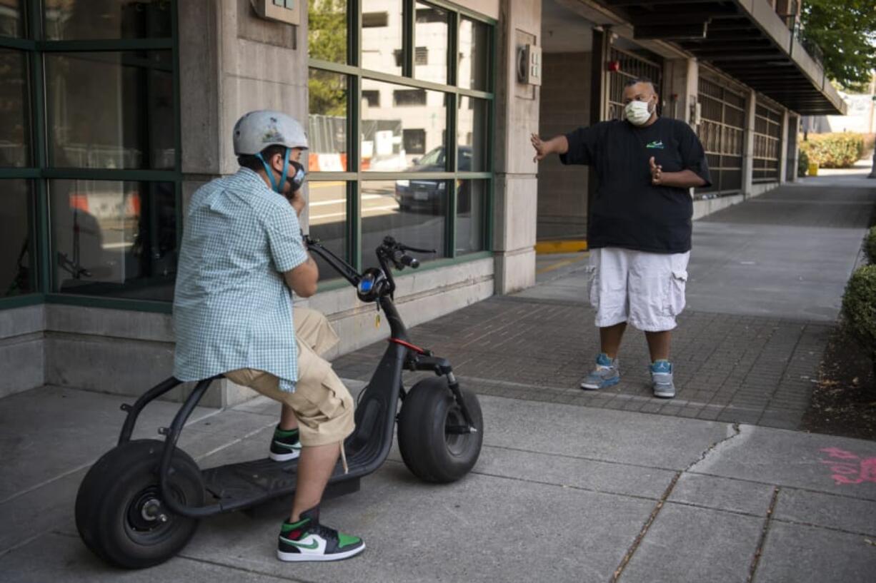 Customer Mark Shelton, left, adjusts his helmet as Zoot Scoot co-owner Jason Adams gives him a safety breakdown outside Zoot Scoot in Vancouver. The electric scooters sales and rental shop opened in June and quickly sold out of inventory. The shop will be getting a new batch of scooters this week for both retail and rental.