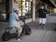 Customer Mark Shelton, left, adjusts his helmet as Zoot Scoot co-owner Jason Adams gives him a safety breakdown outside Zoot Scoot in Vancouver. The electric scooters sales and rental shop opened in June and quickly sold out of inventory. The shop will be getting a new batch of scooters this week for both retail and rental.