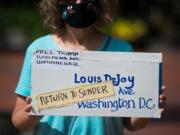 Lisa Jester holds a sign calling for the removal of Louis DeJoy as postmaster general of the United States Postal Service during a protest on Saturday in Vancouver. The protest was part of a nationwide rally for the USPS, organized by MoveOn.org.