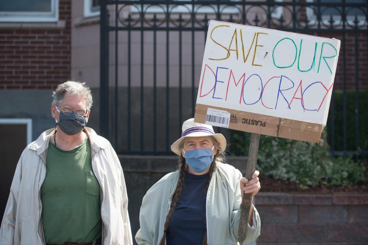 Patrick McChesney, left, and Helen Sareen stand on the side of Columbia Street in Vancouver during a protest advocating for the United States Postal Service on Saturday. The protest was part of a nationwide rally for the USPS, organized by MoveOn.org.