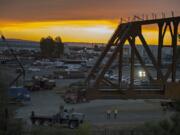 The sun sets as crews move the BNSF railroad truss bridge to a barge on Monday evening. The bridge will be floated about 60 miles up the Columbia River to Drano Lake, where it will be installed to replace a century-old bridge on the rail line.