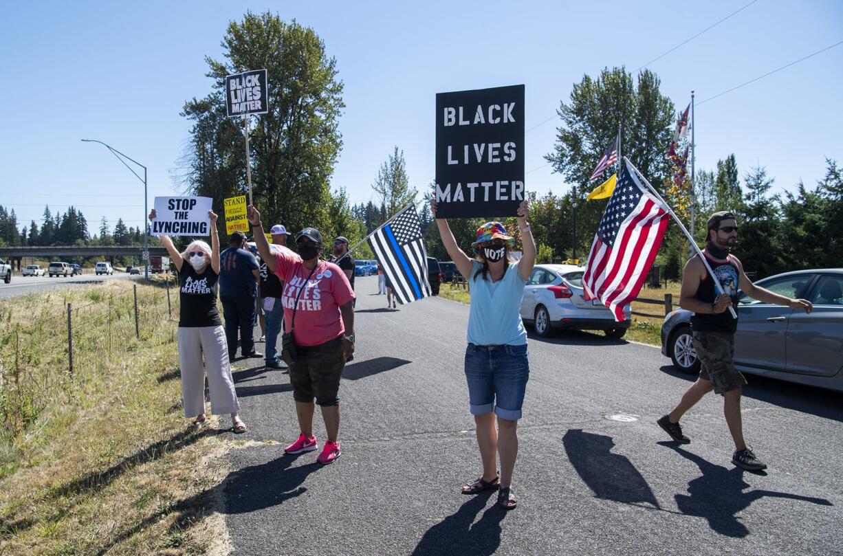 Nancy Shultz, from left, Oletha Wade-Matthews, and Julia Berreth, all of Vancouver, stand with a crowd to protests a Confederate monument and support the Black Lives Matter movement at Jefferson Davis Park near Ridgefield on August 28, 2020. A group of counter protesters, including Josh Vangelder of Battle Ground, right, were also present, waving confederate flags and American flags.