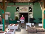 Above, a woman carries a box of produce outside Joe&#039;s Place Farms, which sells more than 25 different fruits and vegetables.