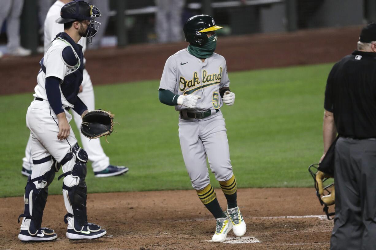 Oakland Athletics' Tony Kemp (5) scores in front of Seattle Mariners catcher Joe Hudson in the 10th inning of a baseball game Saturday, Aug. 1, 2020, in Seattle. The Athletics won 3-2.