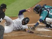 Colorado Rockies' Elias Diaz slides safely across home as Seattle Mariners catcher Austin Nola puts on a late tag in the third inning of a baseball game Friday, Aug. 7, 2020, in Seattle.