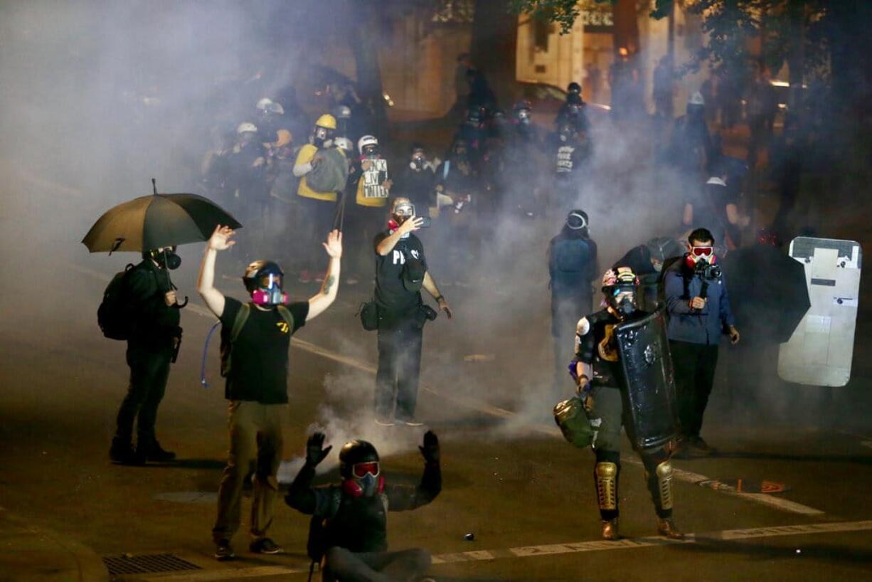 Portland protests return downtown as police use tear gas early, Thursday, Aug. 13, 2020. Protesters and police clashed in downtown Portland in a demonstration that lasted into the predawn hours of Thursday, with some in the crowd setting a fire and exploding commercial grade fireworks outside a federal courthouse that's been a target in months of conflict for Oregon's largest city.