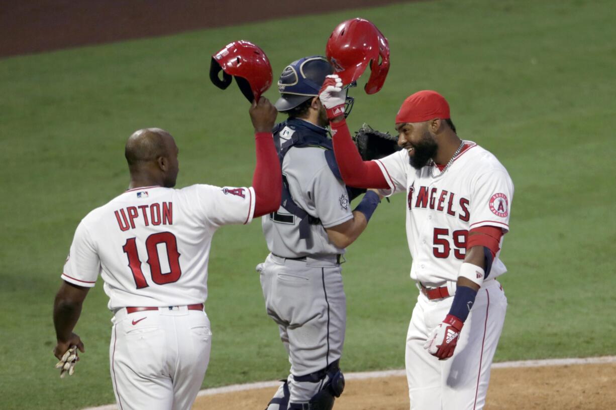 Los Angeles Angels' Jo Adell, right, celebrates his two-run home run with Justin Upton at the plate, next to Seattle Mariners catcher Austin Nola dduring the third inning of a baseball game in Anaheim, Calif., Saturday, Aug. 29, 2020.