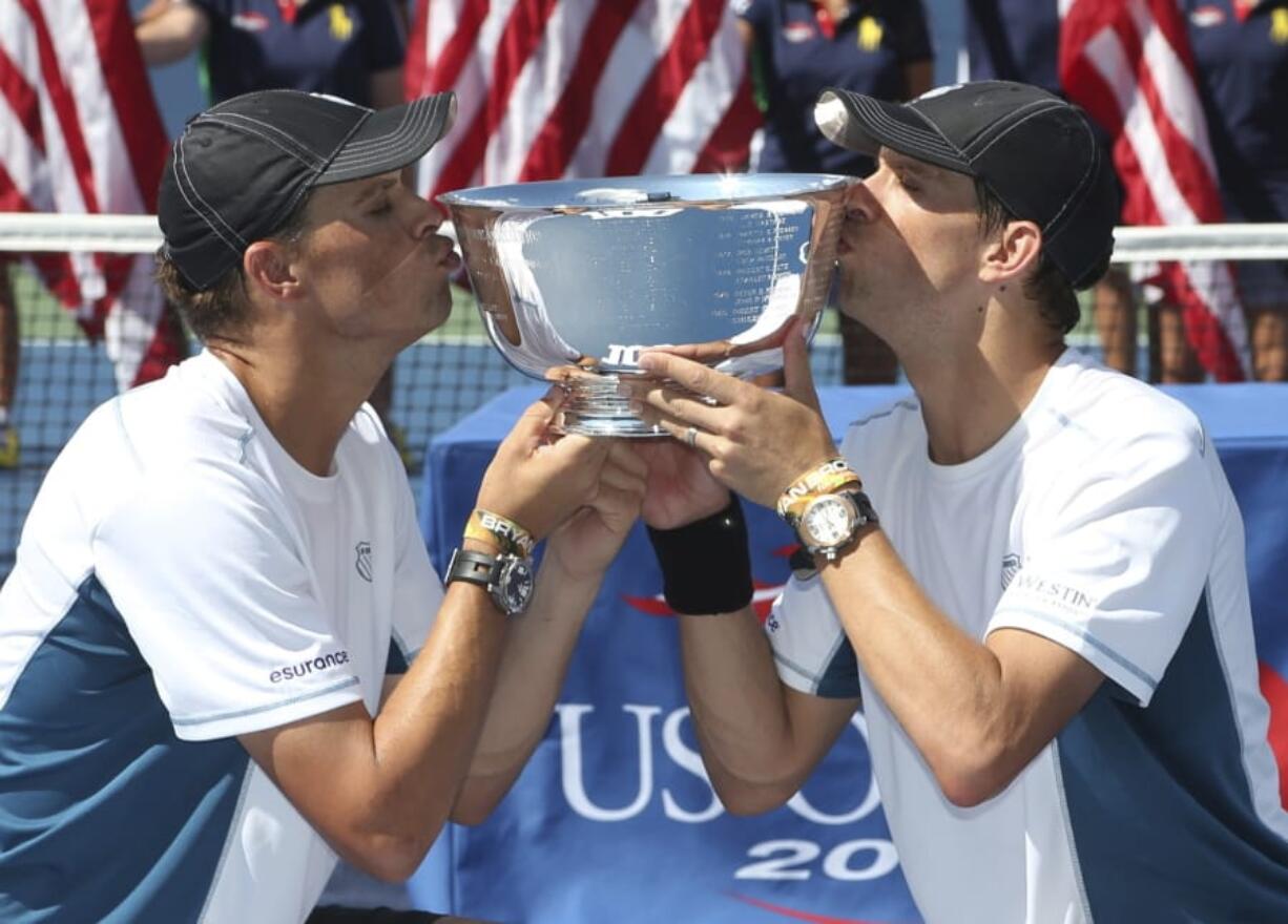 Bob, left, and Mike Bryan kiss the men&#039;s doubles championship trophy after defeating Marc Lopez and Marcel Granollers, of Spain, in the doubles championship match of the 2014 U.S. Open. The win was the Bryan&#039;s 100th tournament title. American twins Bob and Mike Bryan announced their retirement after a record-breaking doubles career,Thursday, Aug. 27, 2020, making official what seemed clear when they did not enter the U.S. Open.