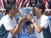 Bob, left, and Mike Bryan kiss the men&#039;s doubles championship trophy after defeating Marc Lopez and Marcel Granollers, of Spain, in the doubles championship match of the 2014 U.S. Open. The win was the Bryan&#039;s 100th tournament title. American twins Bob and Mike Bryan announced their retirement after a record-breaking doubles career,Thursday, Aug. 27, 2020, making official what seemed clear when they did not enter the U.S. Open.