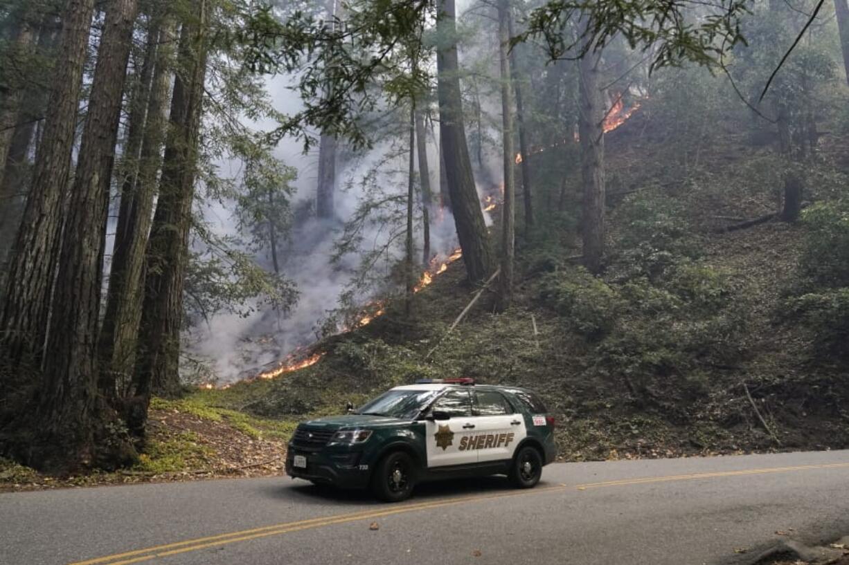 A police vehicle is seen under a forest being burned by the CZU August Lightning Complex Fire Monday, Aug. 24, 2020 near in Bonny Doon, Calif.