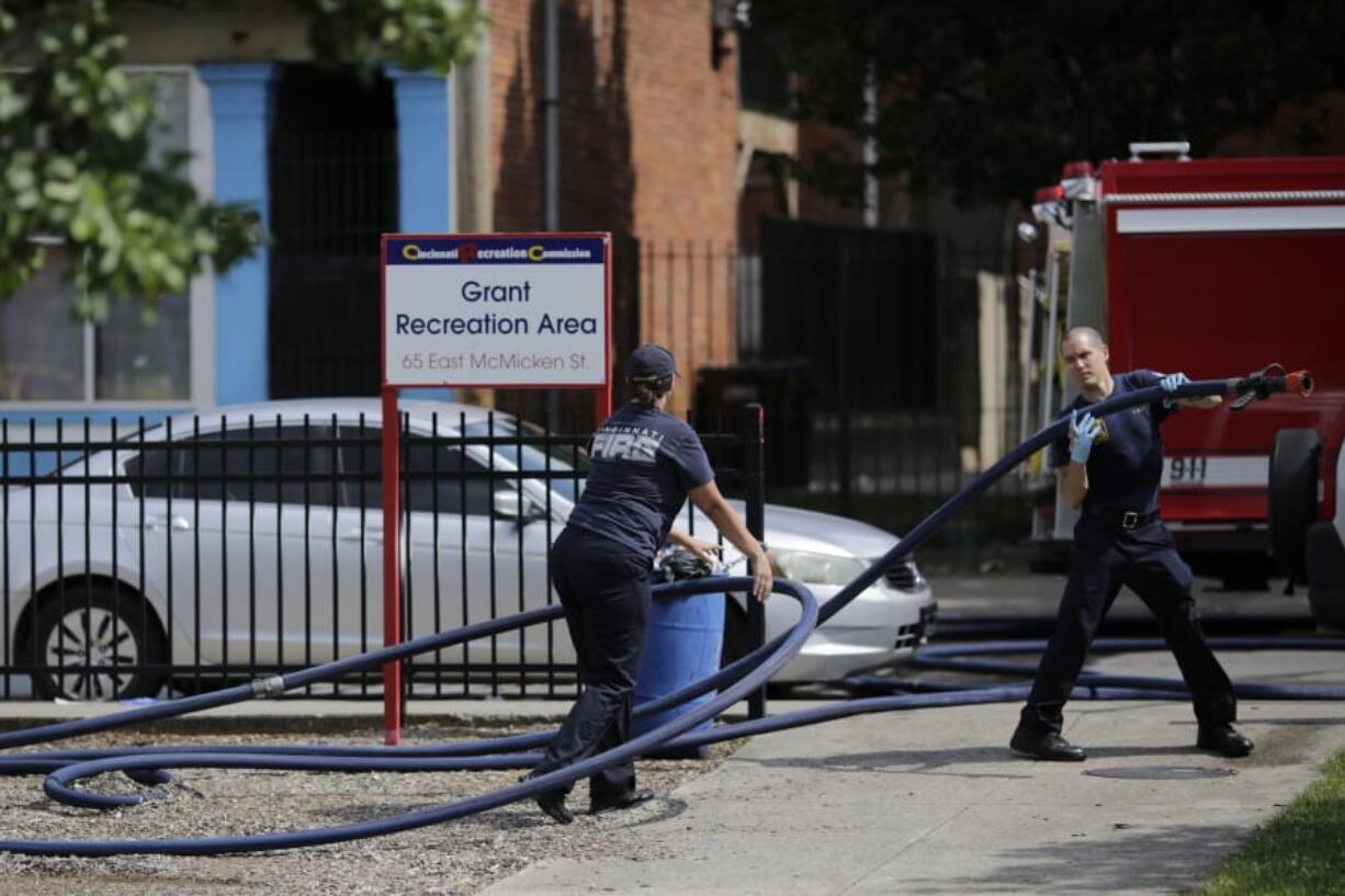 Cincinnati firefighters use bleach and a hose to clean and remove pools of blood left at the scene of a mass shooting near Grant Park in the Over-the-Rhine neighborhood of Cincinnati on Sunday, Aug. 16, 2020. Police confirm that  multiple people are injured and at least three are dead after three separate shootings occurred in the city of Cincinnati within 90 minutes early Sunday morning.