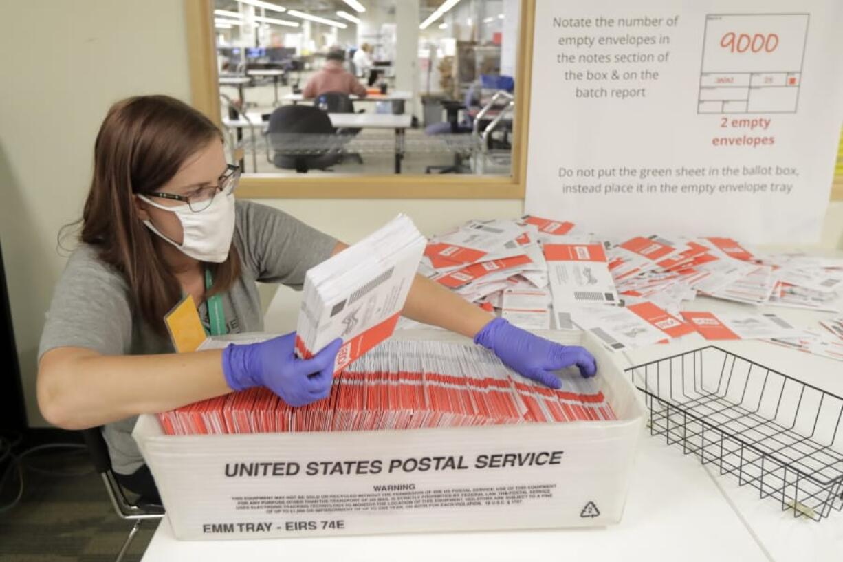 Sydney Freenas wears a mask as she works to process ballots from Tuesday&#039;s primary election that were mailed out to voters and then deposited in drop boxes or mailed back in, Wednesday, Aug. 5, 2020, at the King County Elections headquarters in Renton, Wash., south of Seattle. Washington state has offered voting by mail since 2011. (AP Photo/Ted S.