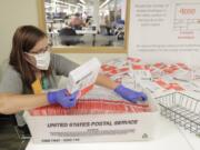 Sydney Freenas wears a mask as she works to process ballots from Tuesday&#039;s primary election that were mailed out to voters and then deposited in drop boxes or mailed back in, Wednesday, Aug. 5, 2020, at the King County Elections headquarters in Renton, Wash., south of Seattle. Washington state has offered voting by mail since 2011. (AP Photo/Ted S.