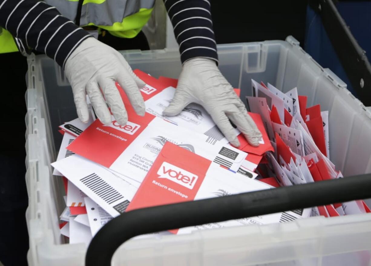 A King County Election worker wearing gloves collect ballots from a drop box March 10 in the Washington State presidential primary in Seattle.