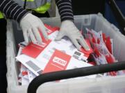 A King County Election worker wearing gloves collect ballots from a drop box March 10 in the Washington State presidential primary in Seattle.