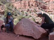 Grand Canyon National Park employees Klara Widrig, left, and Anne Miller examine a rock that revealed fossilized footprints at the Grand Canyon in northern Arizona. Some researchers have estimated the footprints are 313 million years old, among the earliest found at the Grand Canyon.