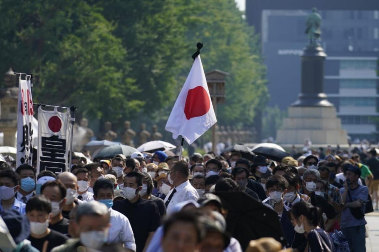 Worshippers queue to pay respects to the war dead at Yasukuni Shrine Saturday, Aug. 15, 2020, in Tokyo. Japan marked the 75th anniversary of the end of World War II.