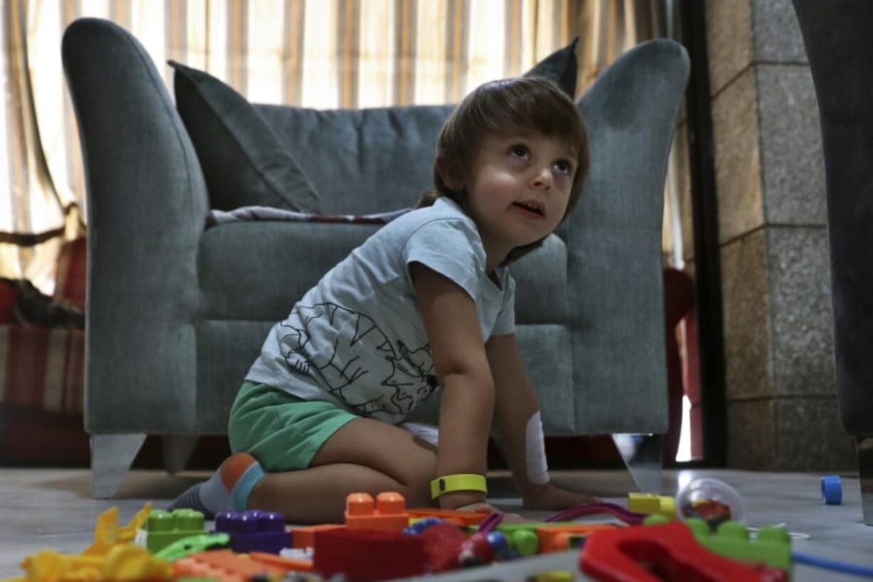 CORRECTS THE FAMILY NAME OF THE BOY - Three-year-old Abed Itani, plays with toys at his family house in Beirut, Lebanon, Tuesday, Aug. 11, 2020. Abed was playing with his Lego blocks when the huge blast ripped through Beirut, shattering the nearby glass doors. He had cuts on his tiny arms and feet, a head injury, and was taken to the emergency room, where he sat amid other bleeding people.