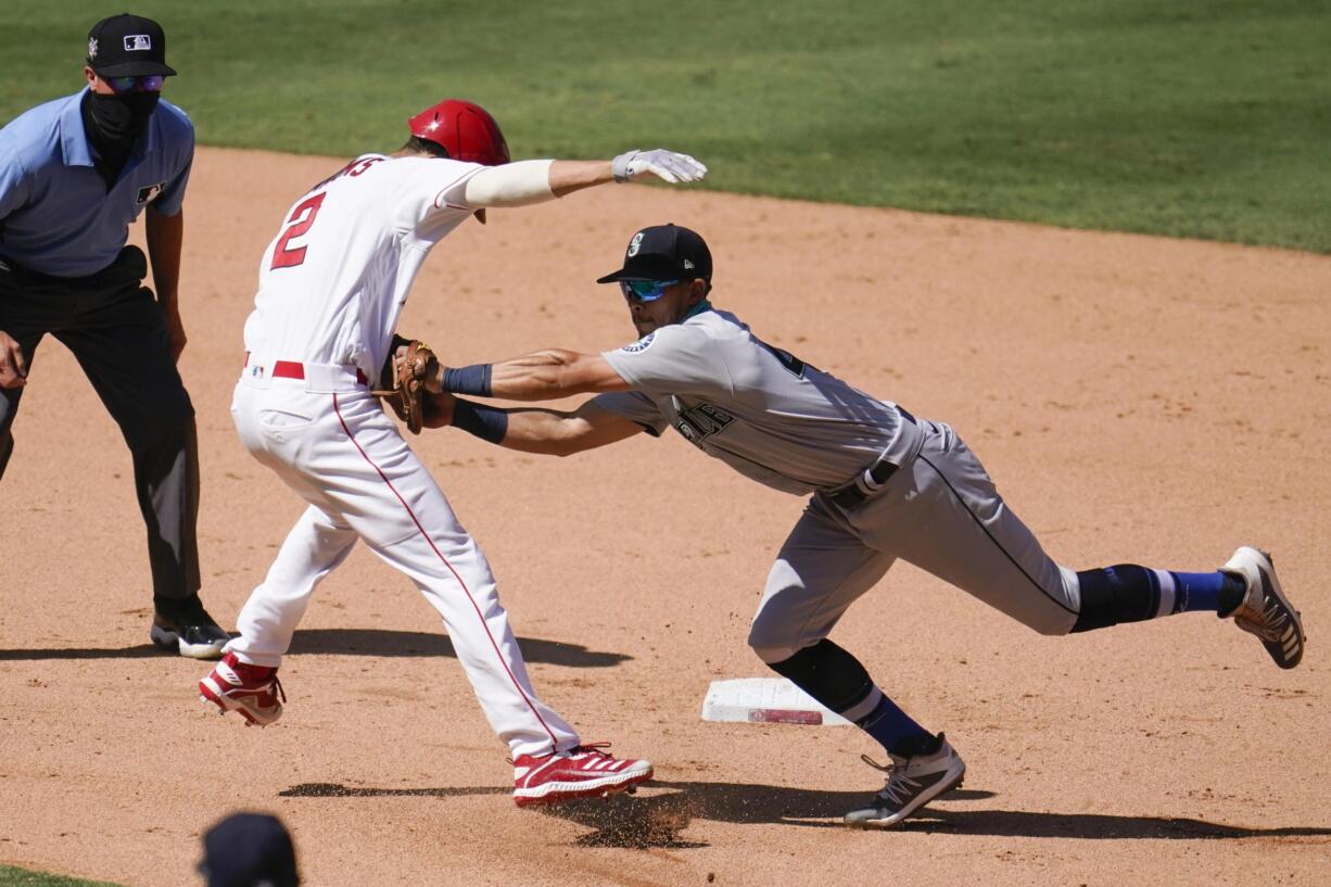 Los Angeles Angels' Andrelton Simmons, front left, is tagged out by Seattle Mariners third baseman Sam Haggerty in a rundown between first and second base during the seventh inning of a baseball game Sunday, Aug. 30, 2020, in Anaheim, Calif. Simmons drove in Albert Pujols with a single on the play.