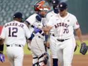 Houston Astros manager Dusty Baker Jr. (12) takes the ball from relief pitcher Andre Scrubb (70) as Scrubb is relieved during the seventh inning of a baseball game against the Seattle Mariners, Sunday, Aug. 16, 2020, in Houston.